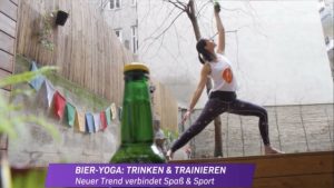 Klaudia im Garten der Yogaria in der Position des Sanften Kriegers, im Vordergrund steht eine Bierflasche