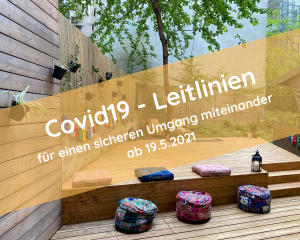 Das Yogadeck im Garten der Yogaria, schön dekoriert mit bunten Sitzkissen und Laternen, eine Yogamatte liegt am Ende des Yogadecks
