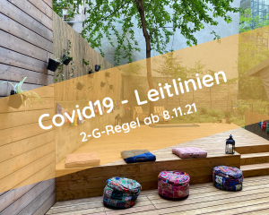 Das Yogadeck im Garten der Yogaria mit den bunten Sitzkisssen und einer Laterne