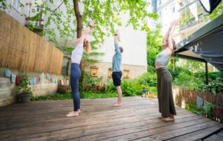 3 Yogis von der Seite fotografiert in der Position des Berges mit gestreckten Händen zum Himmel