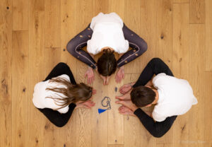 Foto 3 Personen praktizieren Yoga im Kreis