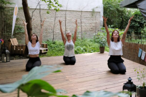 Foto 3 Personen praktizieren Yoga im Garten
