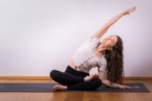 Ari in einer Yogaposition sitzt auf ihrer Matte